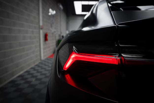 Close-up of a black car's rear with red taillight in a garage setting